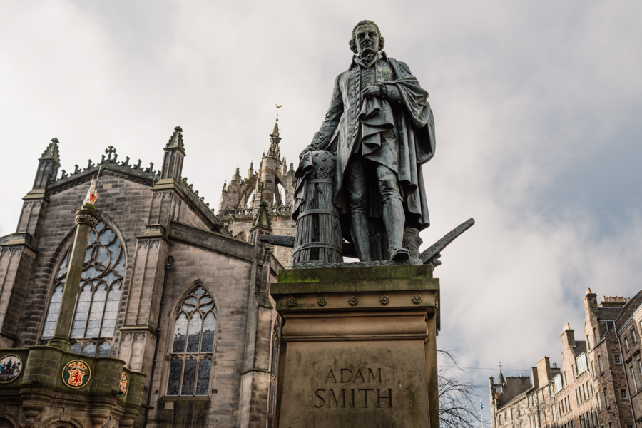 A statue of Adam Smith in front of the gothic St Giles Cathedral and Mercat Cross in Edinburgh.