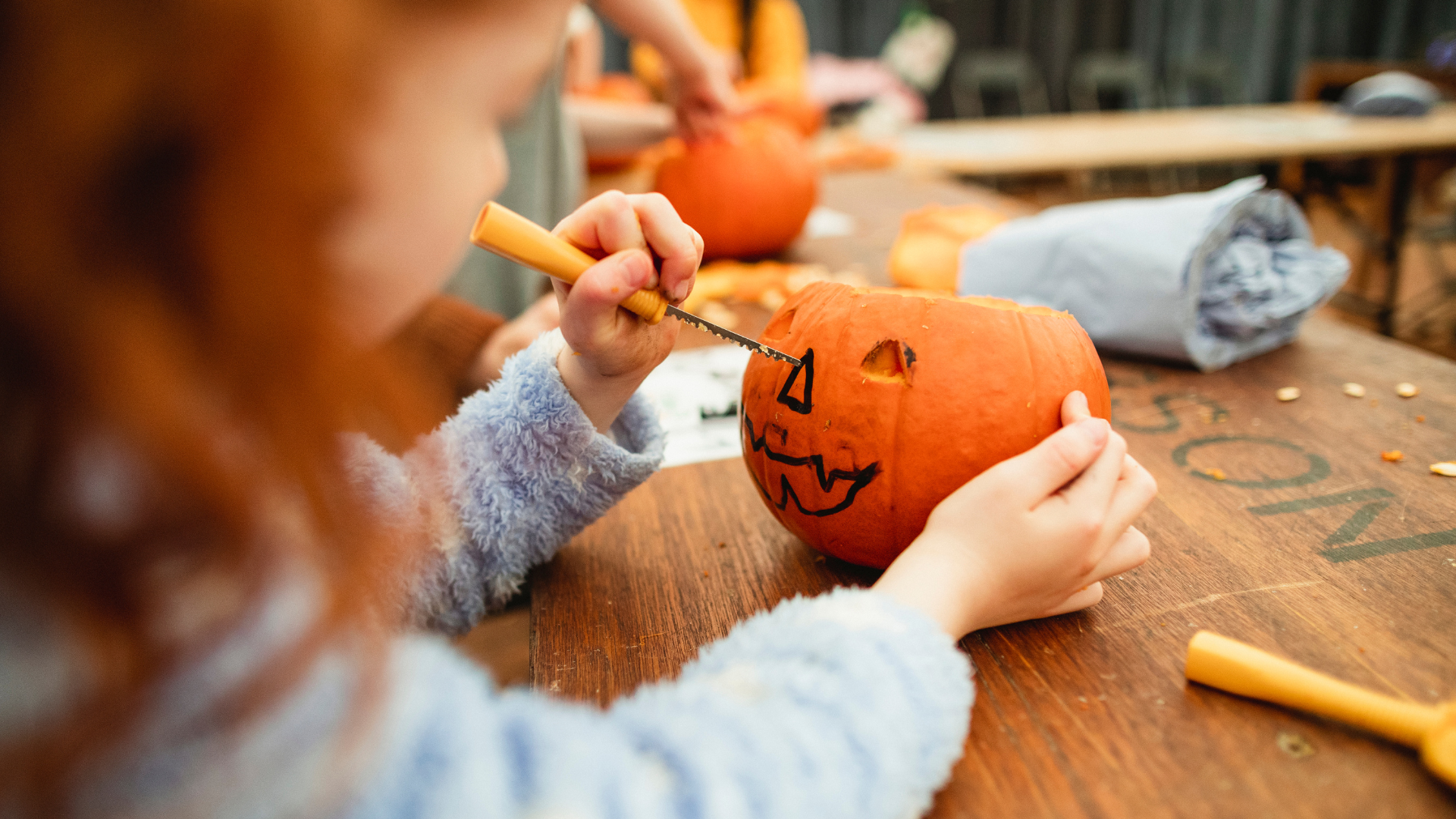 A young child carves a pumpkin jack-o-lantern for Halloween in Edinburgh.