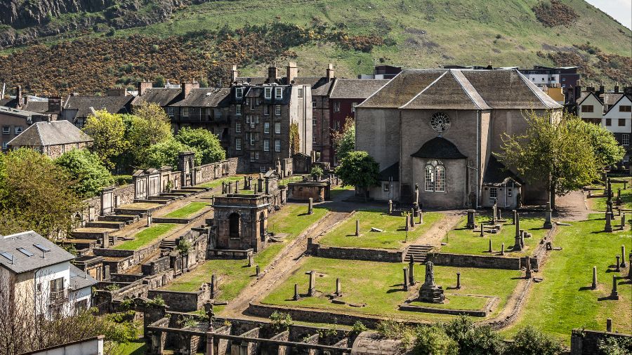 Canongate Graveyard in Edinburgh, with green grass and old headstones scattered around in different sizes and shapes.