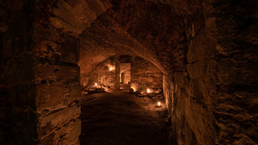 A series of candlelit rooms with arched ceilings in the Edinburgh vaults, as seen on an underground ghost tour in Edinburgh.