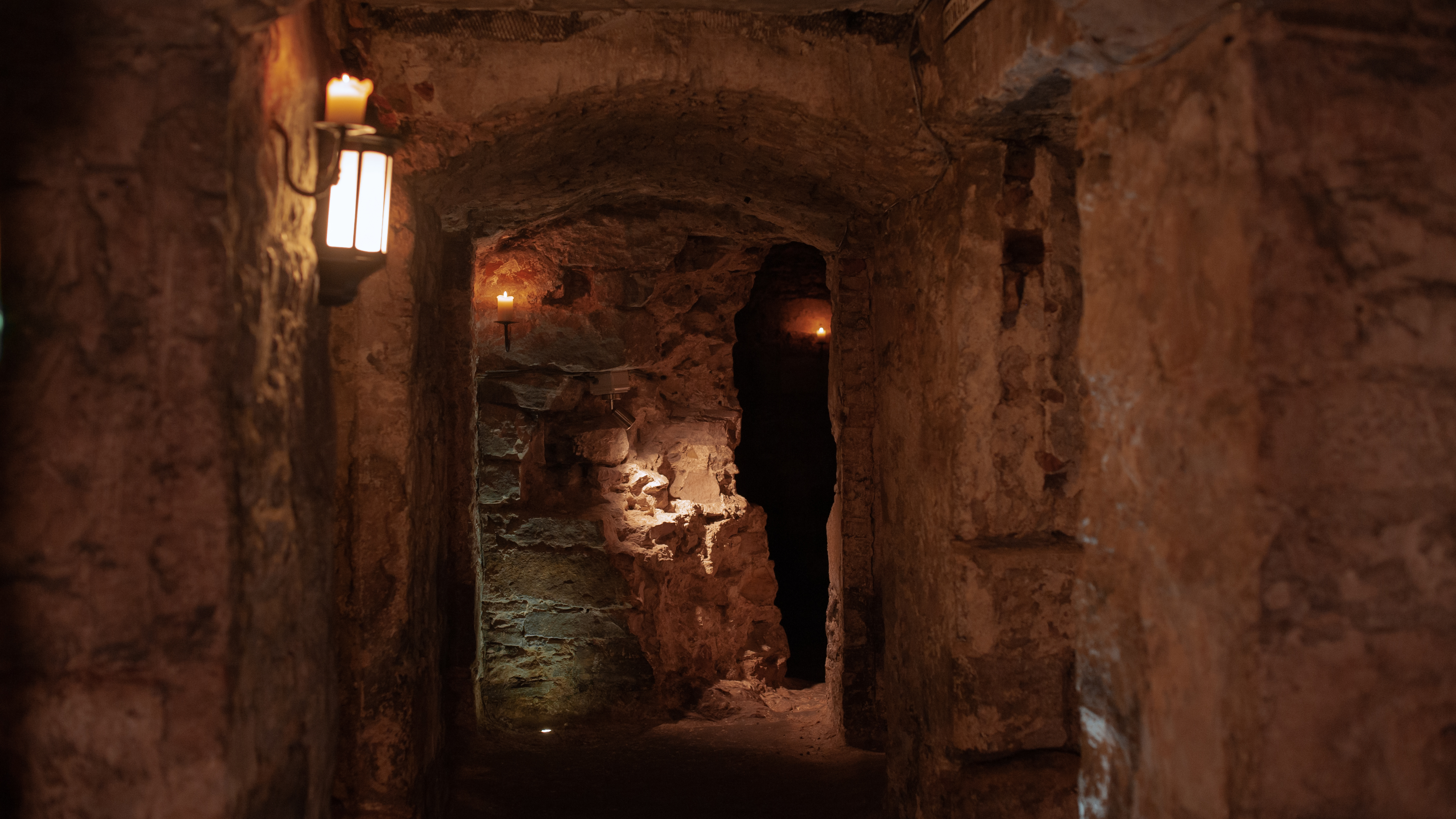 A candlelit stone corridor underground in Edinburgh's Blair Street Underground Vaults 