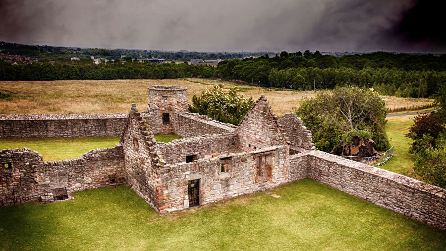 A photo of stone building ruins and countryside hills.