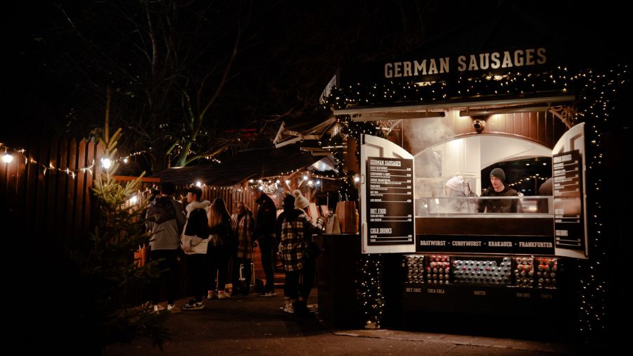 A German sausage stall at the Edinburgh Christmas Market at night.