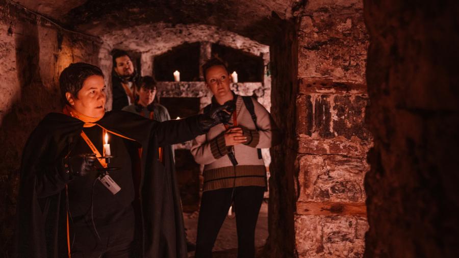A Mercat Storyteller leading a group of guests through the Blair Street Underground Vaults on a ghost tour of Edinburgh.
