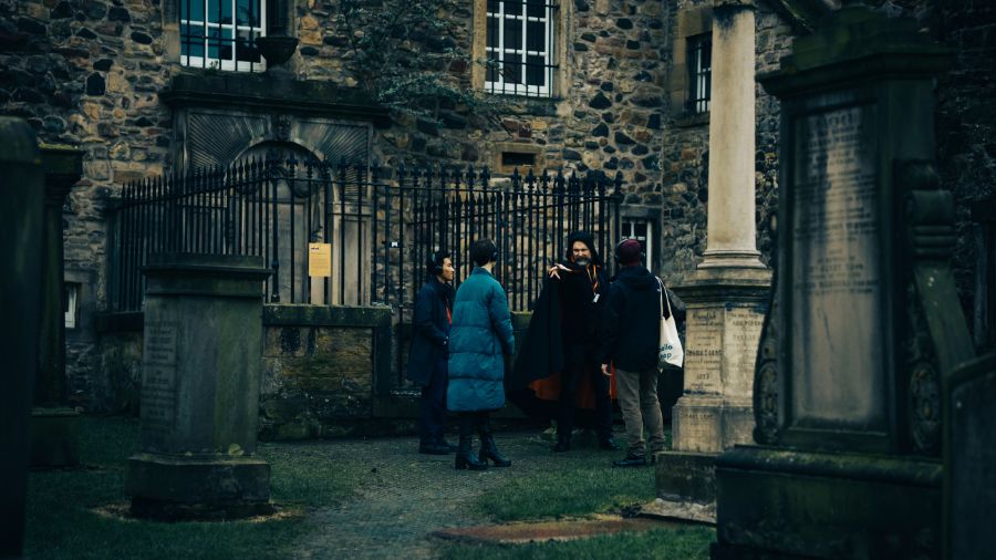 A Mercat Storyteller leads a group of 3 visitors on an Edinburgh graveyard tour in Canongate Kirkyard.