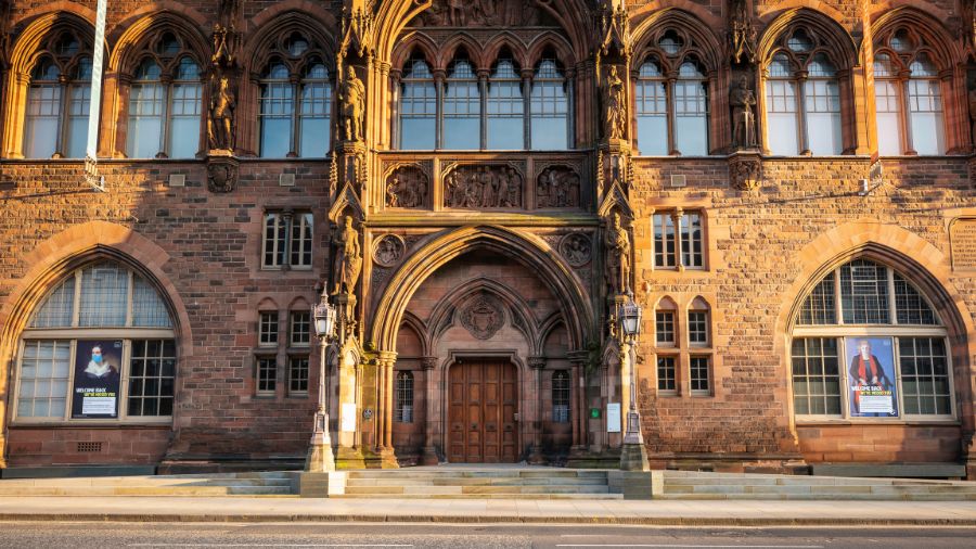 The front entrance to the National Portrait Gallery Scotland, featuring intricately detailed carvings in red sandstone and gothic window details.