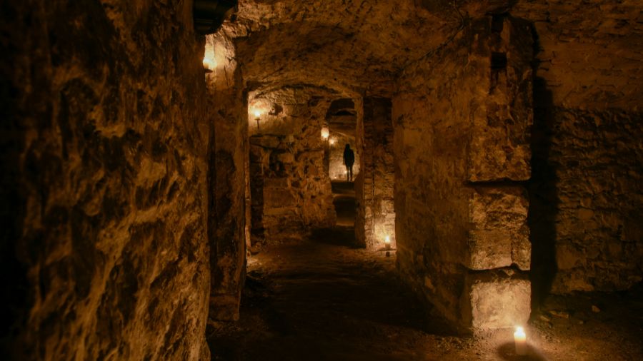 A series of rooms and corridors in the Blair Street Underground Vaults with the silhouette of a person at the end.