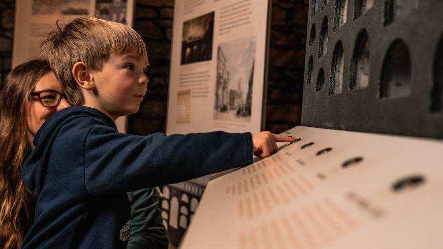 A child pushes a button on an interactive display in the Edinburgh Vaults Museum at the end of a Gory Stories tour.