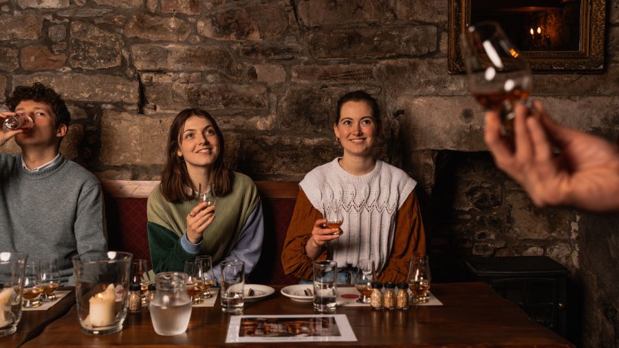 Three guests in the Edinburgh underground Megget’s Cellar, being led in a whisky tasting. 