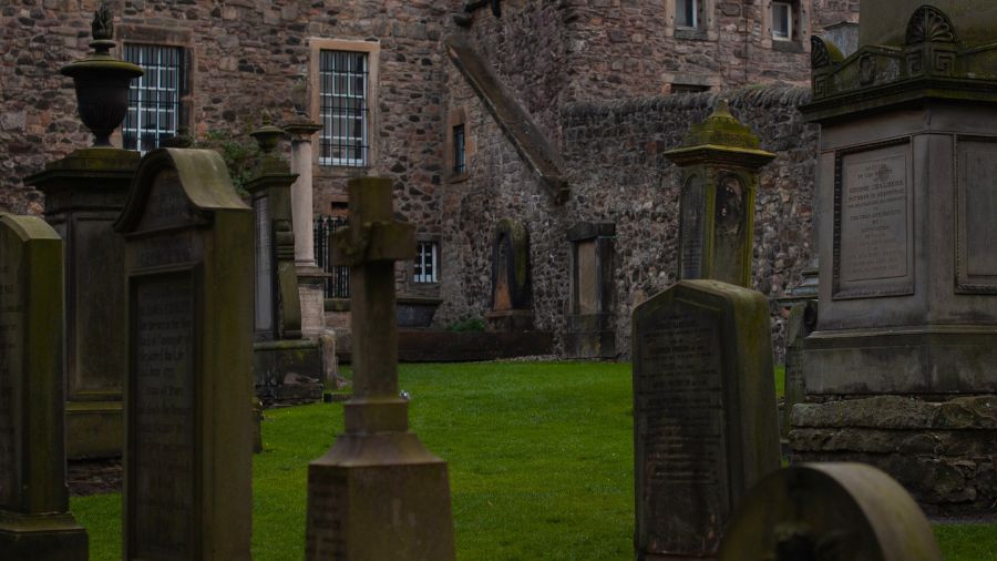 Canongate Graveyard in Edinburgh, with green grass and old headstones scattered around in different sizes and shapes. 