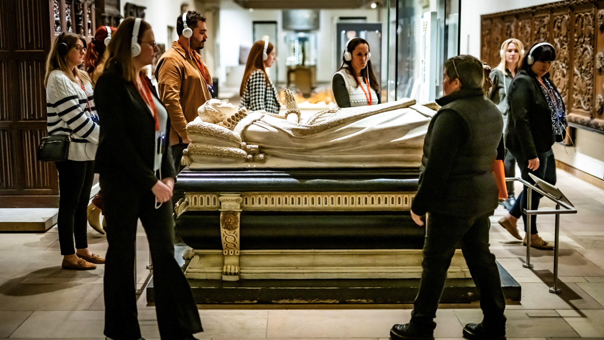 A Mercat Storyteller and several visitors wearing white headphones gathered around a white effigy of Mary Queen of Scots. 