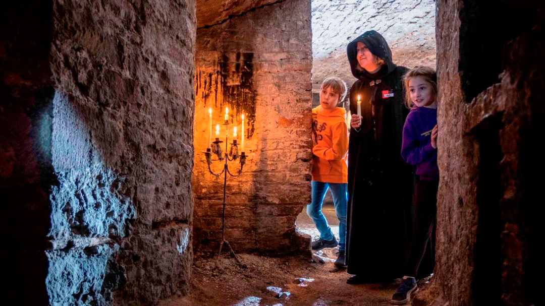 A Mercat storyteller exploring the Blair Street Underground Vaults with two kids on tour. 