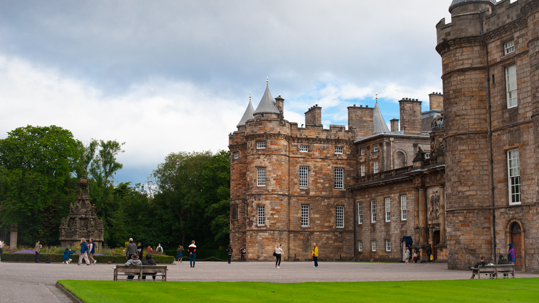 The front of Holyrood Palace and its courtyard, with lots of people milling around. 