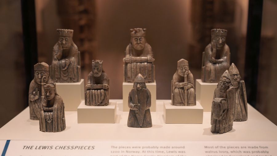 10 light brown ivory chess pieces on display in a case at the National Museum of Scotland.