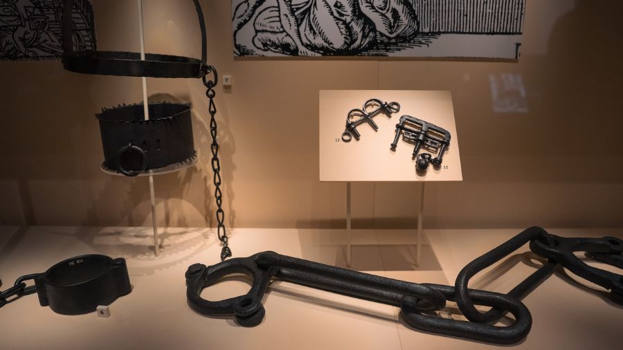 A display of iron interrogation instruments from the Scottish Witch Trials, including a collar, chains, and thumbscrews. 