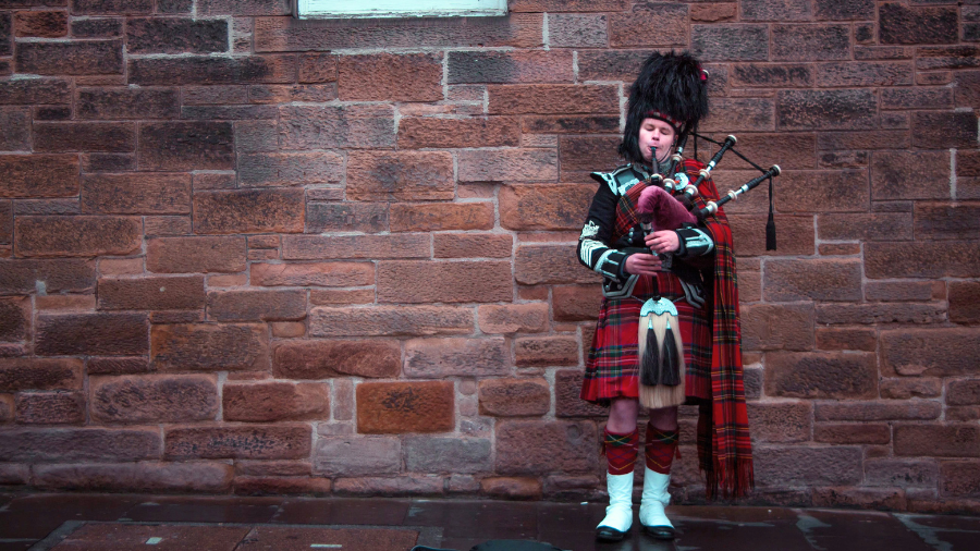 A Scottish bagpiper in a kilt playing on the Royal Mile in Edinburgh.