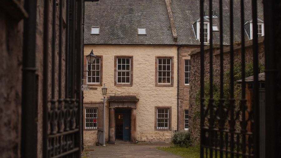 A 16th-century building in Tweeddale Court in Edinburgh, framed by and iron gate.